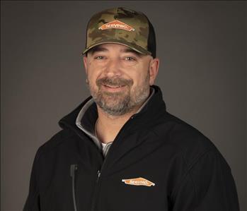 male servpro employee wearing baseball cap in front of blank background